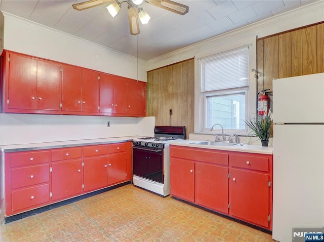 kitchen with red cabinetry, a sink, white appliances, crown molding, and light countertops