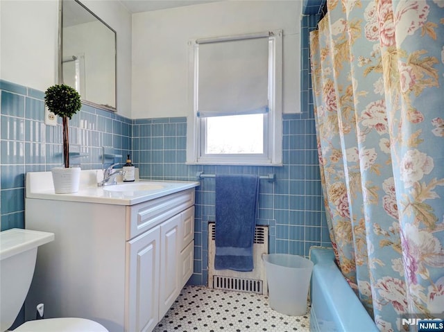 full bathroom featuring vanity, radiator, shower / bathtub combination with curtain, tile walls, and toilet