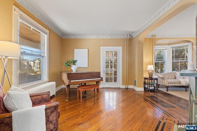 sitting room with radiator, wood finished floors, baseboards, and ornamental molding