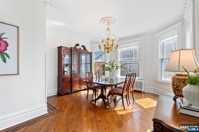 dining space featuring an inviting chandelier, wood finished floors, radiator heating unit, and crown molding