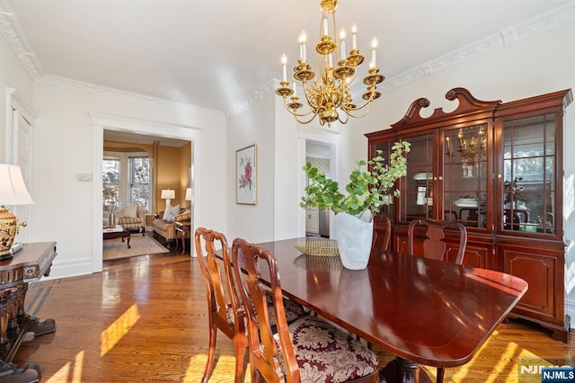 dining room featuring baseboards, crown molding, an inviting chandelier, and wood finished floors