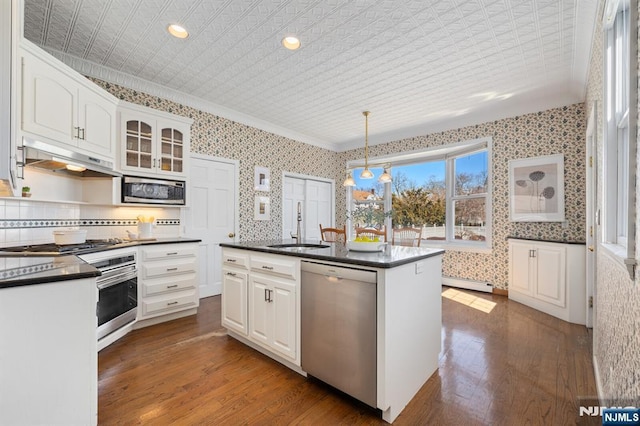 kitchen featuring a sink, stainless steel appliances, dark countertops, and wallpapered walls