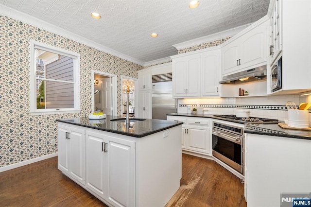 kitchen featuring under cabinet range hood, stainless steel appliances, a sink, and wallpapered walls