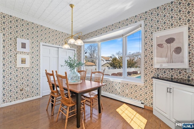 dining room featuring a baseboard radiator, baseboards, wood finished floors, and wallpapered walls