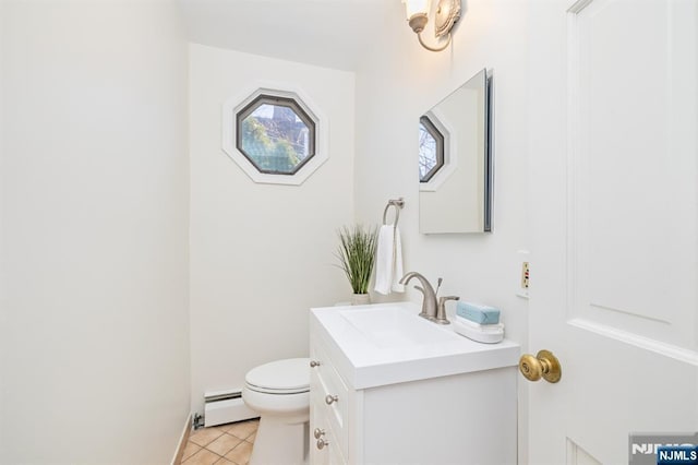 half bathroom with a baseboard heating unit, toilet, vanity, and tile patterned flooring