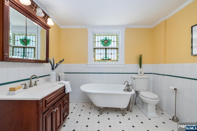 full bath with plenty of natural light, ornamental molding, vanity, and a freestanding tub