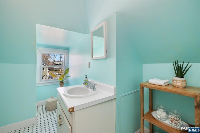 bathroom with vanity, lofted ceiling, and baseboards