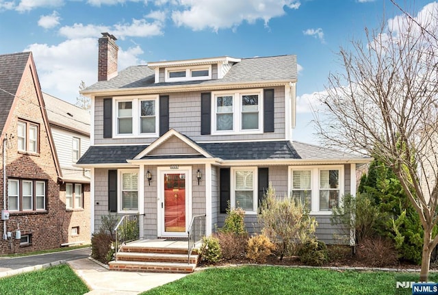 traditional style home with a chimney and a shingled roof