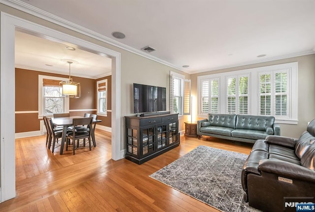 living room featuring visible vents, light wood-type flooring, baseboards, and ornamental molding