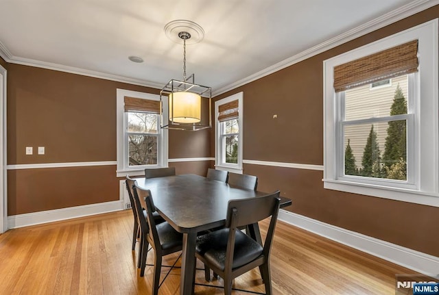 dining space featuring baseboards, light wood-style floors, and ornamental molding