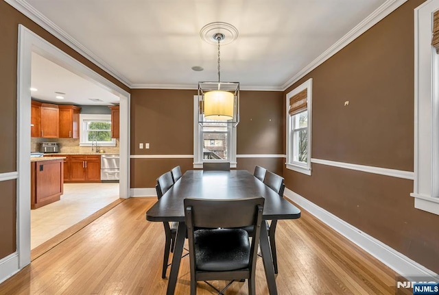 dining area featuring baseboards, light wood-style floors, and ornamental molding