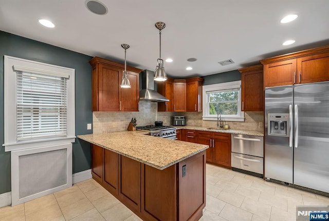 kitchen with visible vents, a peninsula, a sink, appliances with stainless steel finishes, and wall chimney range hood