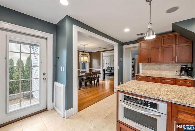 kitchen featuring oven, tasteful backsplash, light tile patterned flooring, and brown cabinetry