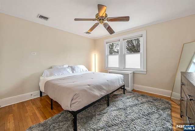 bedroom with visible vents, light wood-type flooring, baseboards, and ornamental molding