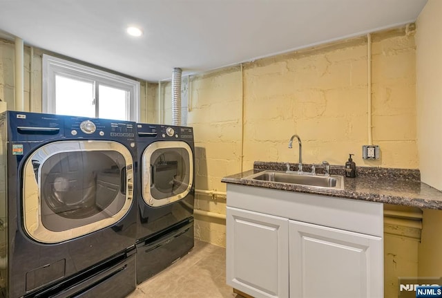 clothes washing area with a sink, cabinet space, and washer and clothes dryer