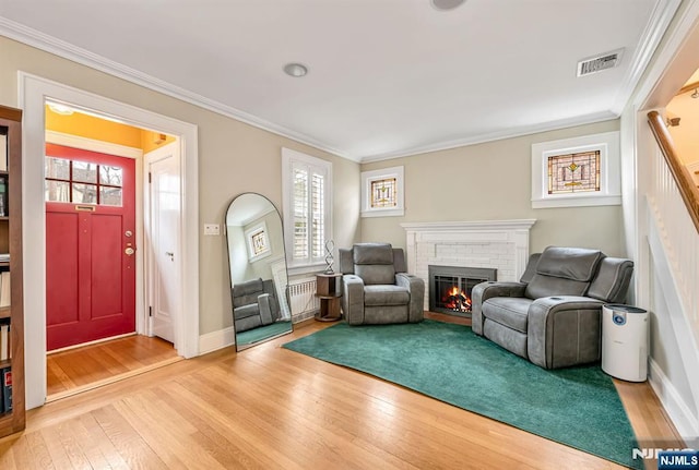 sitting room with visible vents, a fireplace, crown molding, and hardwood / wood-style flooring