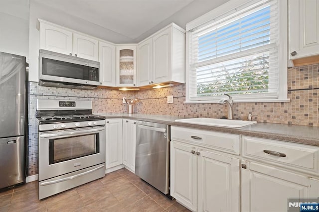 kitchen featuring a sink, stainless steel appliances, backsplash, and white cabinets