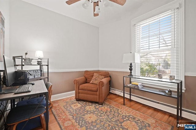 office featuring ceiling fan, wood finished floors, baseboard heating, and wainscoting