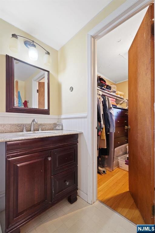 bathroom with a spacious closet, a wainscoted wall, tile patterned floors, and vanity