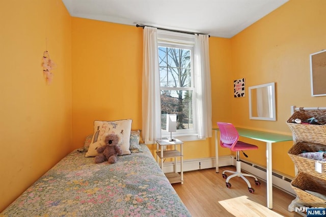 bedroom with a baseboard heating unit and wood finished floors