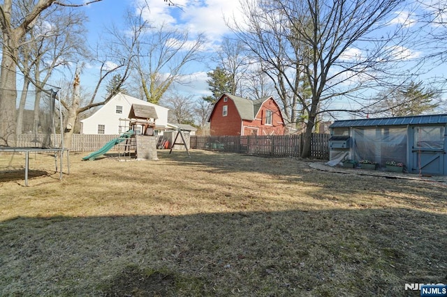 view of yard featuring a fenced backyard, an outdoor structure, a storage unit, a playground, and a trampoline