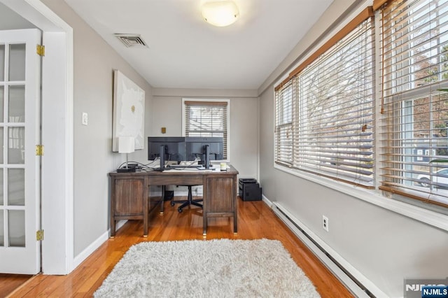 office with visible vents, a baseboard radiator, baseboards, and wood finished floors