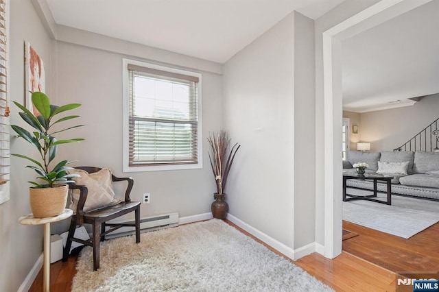 living area featuring stairway, a baseboard heating unit, baseboards, and wood finished floors