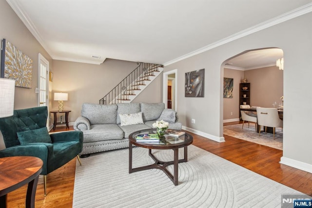 living room featuring dark wood-type flooring, baseboards, stairs, ornamental molding, and arched walkways