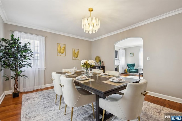 dining space with an inviting chandelier, wood finished floors, arched walkways, and baseboards