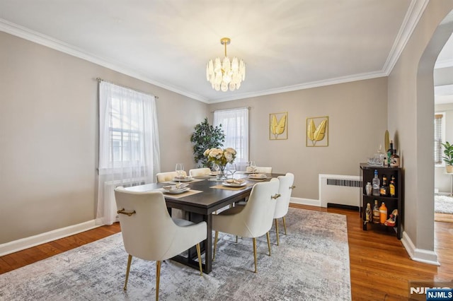 dining room with arched walkways, a notable chandelier, radiator, and wood finished floors