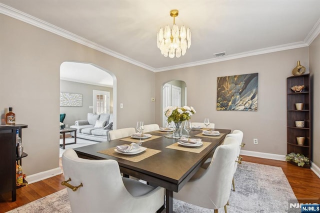 dining space with baseboards, visible vents, arched walkways, dark wood-style flooring, and a chandelier