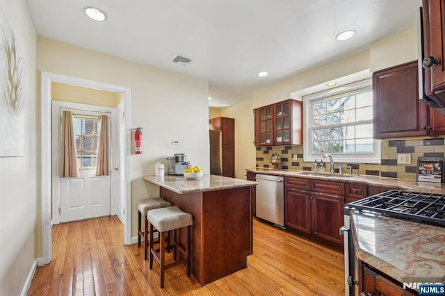 kitchen with visible vents, a kitchen bar, appliances with stainless steel finishes, dark brown cabinets, and a healthy amount of sunlight