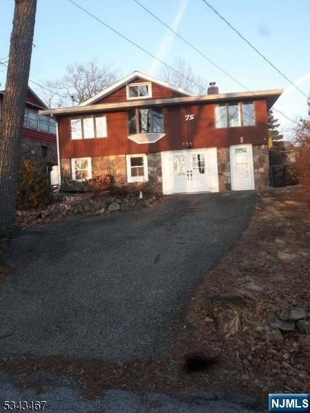 view of front of property with aphalt driveway, stone siding, and a chimney