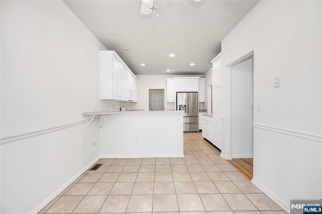 kitchen featuring light tile patterned floors, visible vents, a peninsula, white cabinets, and stainless steel refrigerator with ice dispenser