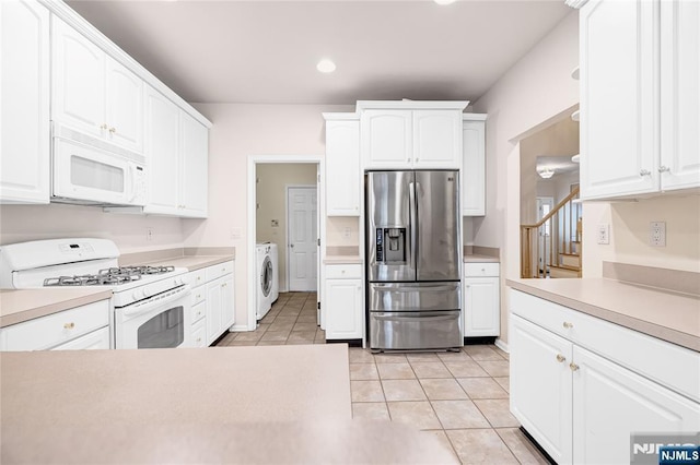 kitchen with white appliances, washer / clothes dryer, light tile patterned flooring, light countertops, and white cabinetry