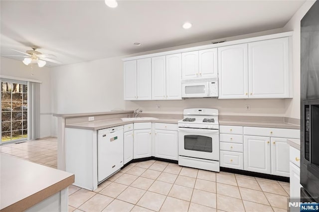 kitchen with white appliances, white cabinetry, a peninsula, and a sink