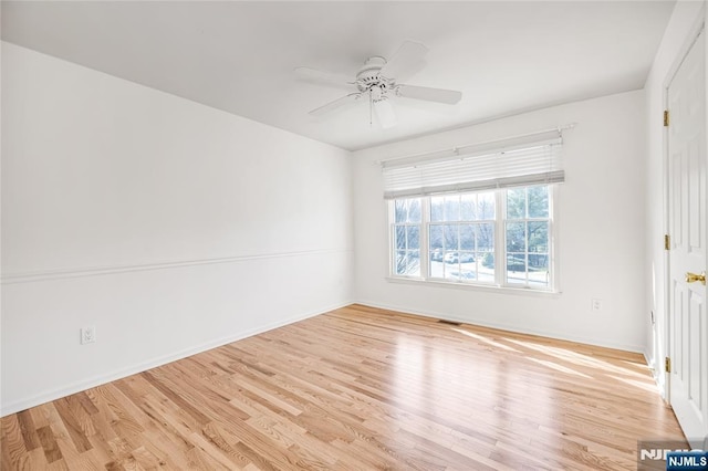 spare room featuring light wood-type flooring, baseboards, visible vents, and ceiling fan