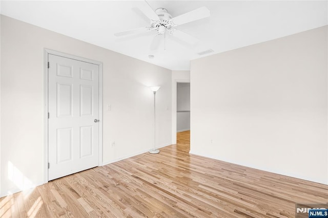 empty room with light wood finished floors and a ceiling fan