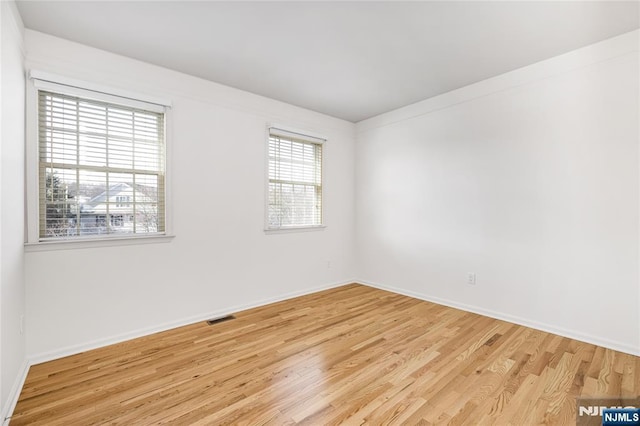 unfurnished room featuring light wood-style flooring, baseboards, and visible vents