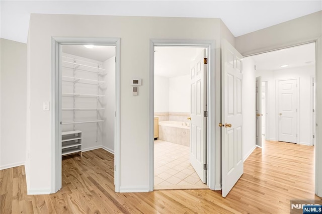 hallway featuring light wood-style floors and baseboards