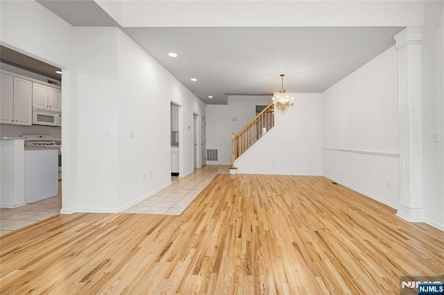 unfurnished living room with visible vents, recessed lighting, stairway, light wood-style floors, and an inviting chandelier