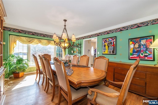 dining room with wainscoting, ornamental molding, an inviting chandelier, and wood finished floors