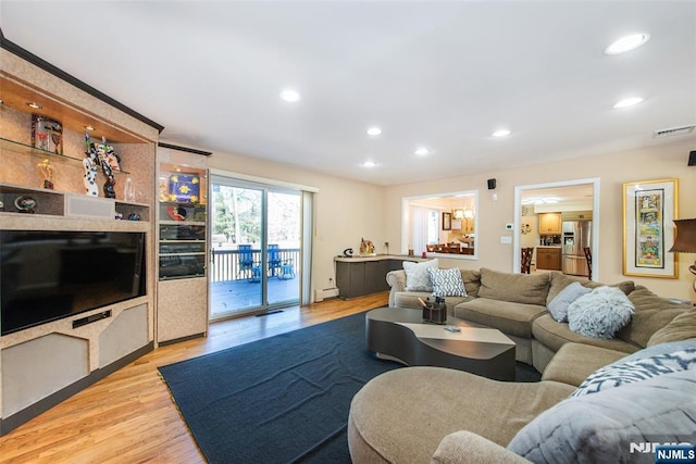 living room featuring a baseboard heating unit, recessed lighting, wood finished floors, and visible vents