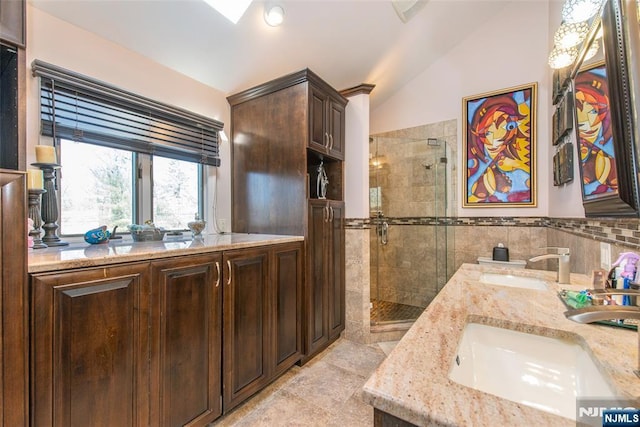 full bath with vaulted ceiling, double vanity, a stall shower, and a sink