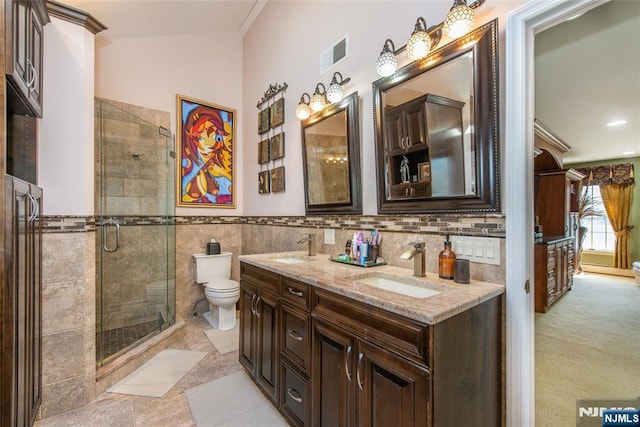 bathroom featuring tile walls, toilet, visible vents, and a sink