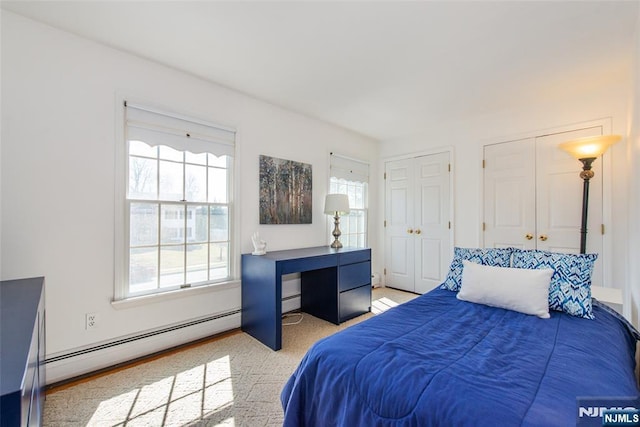 bedroom with a baseboard radiator and two closets