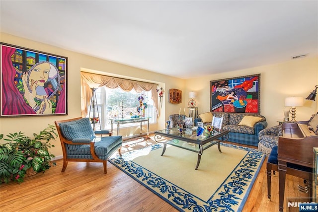 living area featuring visible vents, baseboards, and wood finished floors