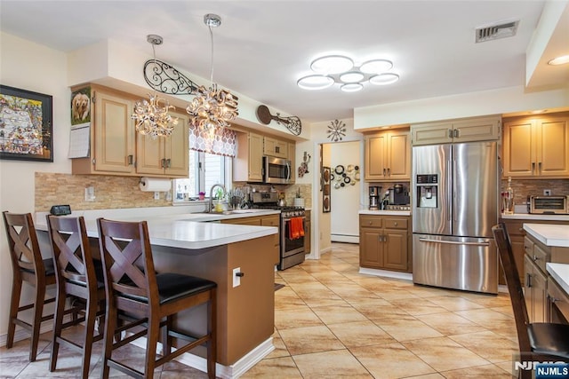 kitchen with visible vents, stainless steel appliances, a peninsula, light countertops, and a chandelier