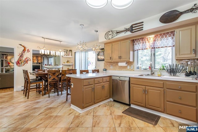 kitchen featuring a peninsula, a sink, light countertops, stainless steel dishwasher, and tasteful backsplash