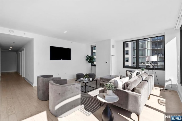 living room with hardwood / wood-style flooring, visible vents, and baseboards